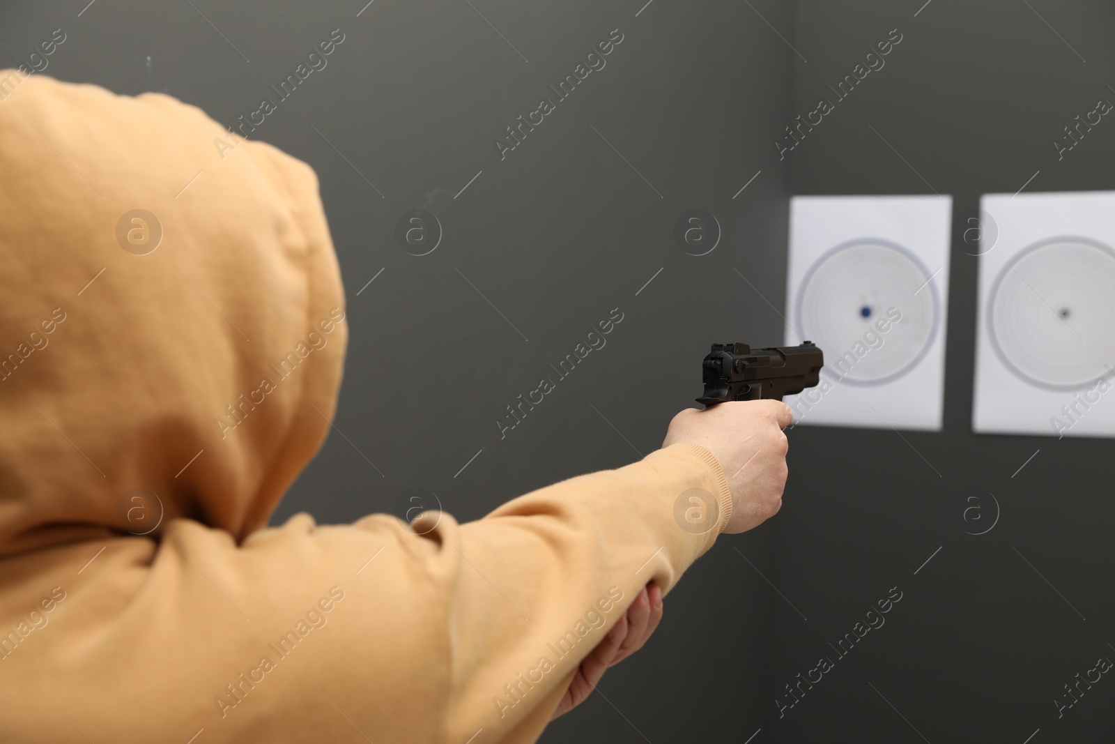 Photo of Man aiming at shooting target indoors, selective focus