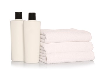 Folded soft terry towels with cosmetic products on white background