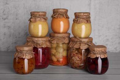 Photo of Many glass jars with different preserved products on wooden table