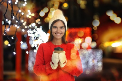 Image of Happy beautiful woman with paper cup of mulled wine at Christmas fair