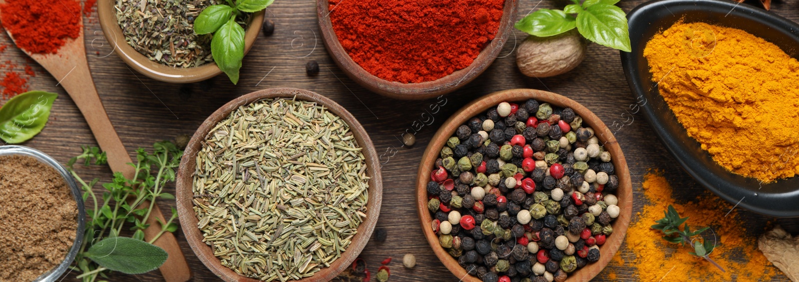 Image of Different herbs and spices on wooden table, flat lay. Banner design