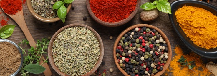 Image of Different herbs and spices on wooden table, flat lay. Banner design