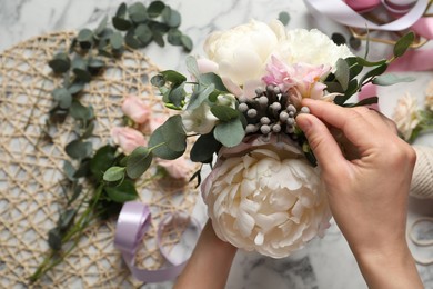 Florist creating beautiful bouquet at white marble table, closeup