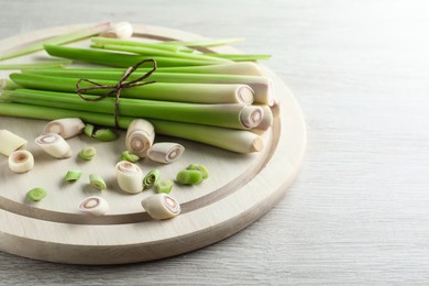 Whole and cut fresh lemongrass on white wooden table