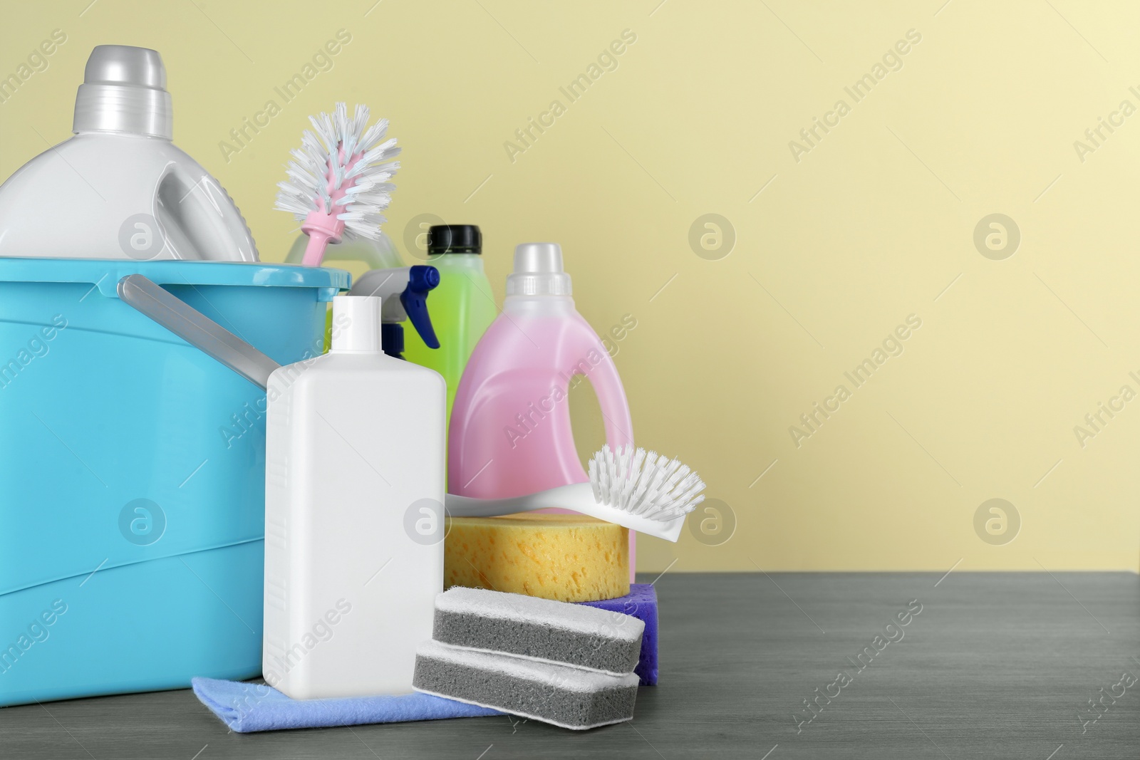 Photo of Different cleaning supplies and tools on wooden table against beige, space for text