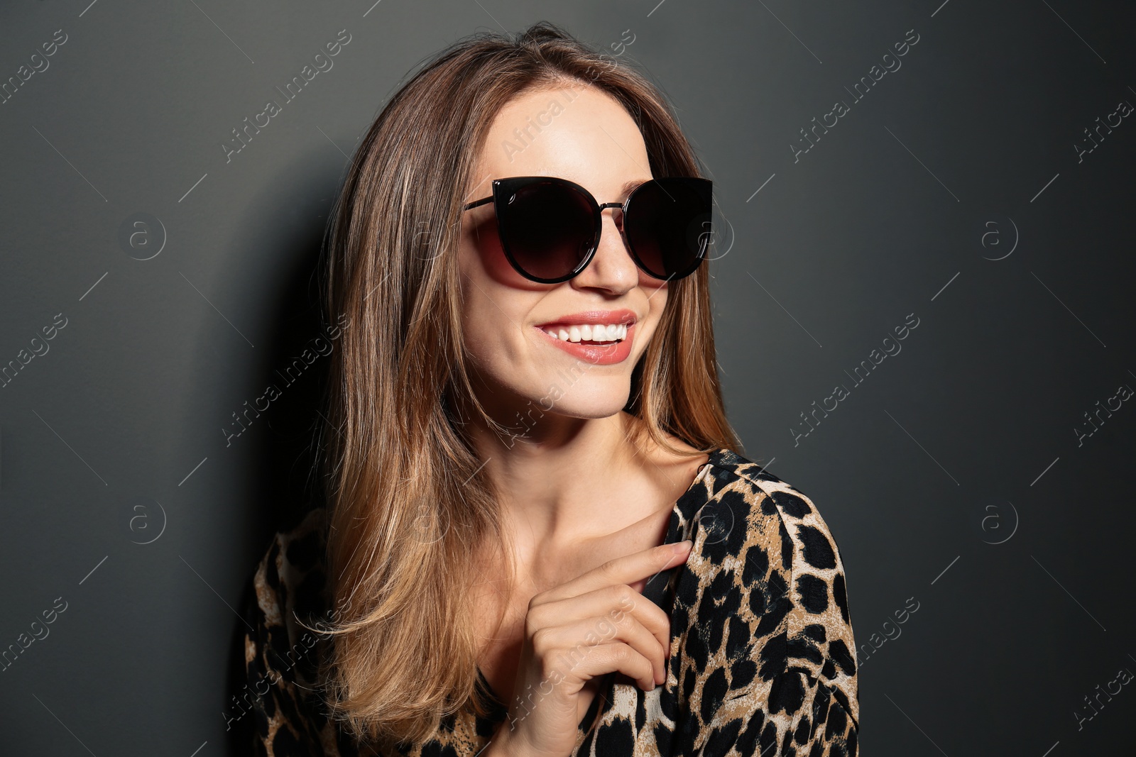 Photo of Young woman wearing stylish sunglasses on dark grey background