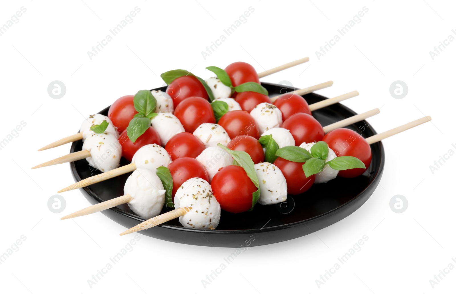 Photo of Plate of Caprese skewers with tomatoes, mozzarella balls, basil and spices isolated on white