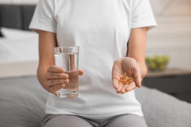 Photo of Woman with pills and glass of water on bed in room. Weight loss