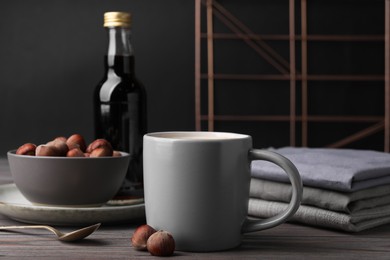 Photo of Mug of delicious coffee with hazelnut syrup on wooden table