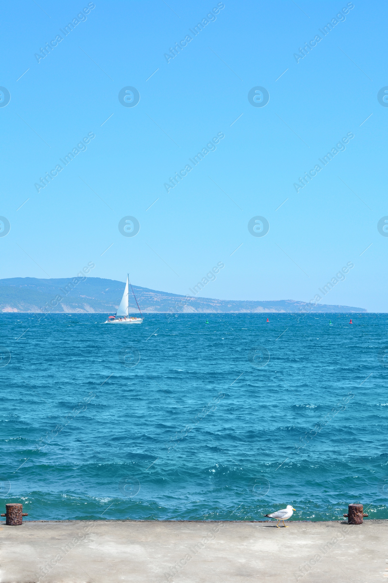 Photo of Beautiful seascape with concrete pier and sailboat on sunny day