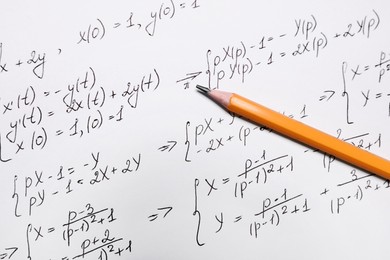 Photo of Sheet of paper with mathematical formulas and pencil, top view