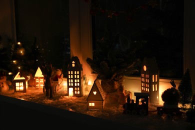 Christmas atmosphere. Beautiful glowing houses and toys on window sill indoors
