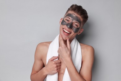 Handsome man with clay mask on his face against light grey background