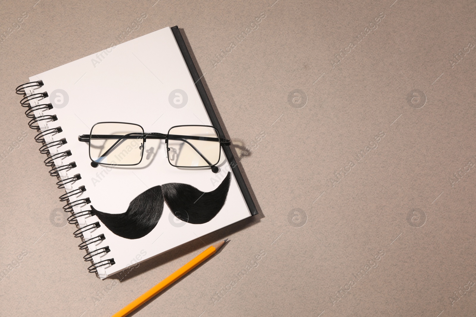 Photo of Flat lay composition with artificial moustache and glasses on light brown background, space for text