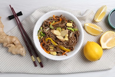 Photo of Stir-fry. Delicious cooked noodles with chicken and vegetables in bowl served on light wooden table, flat lay