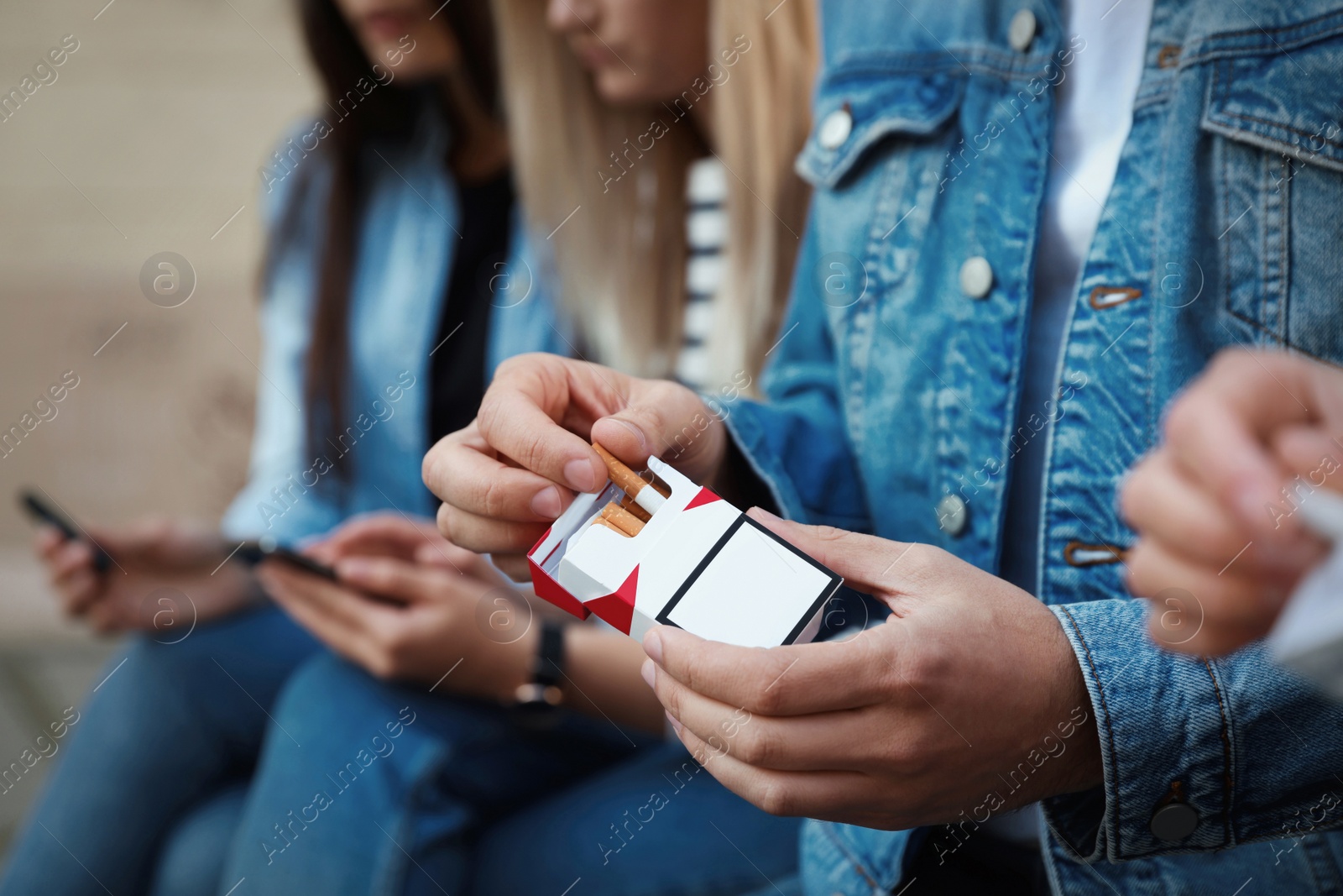 Photo of Man taking cigarette out of pack outdoors, closeup