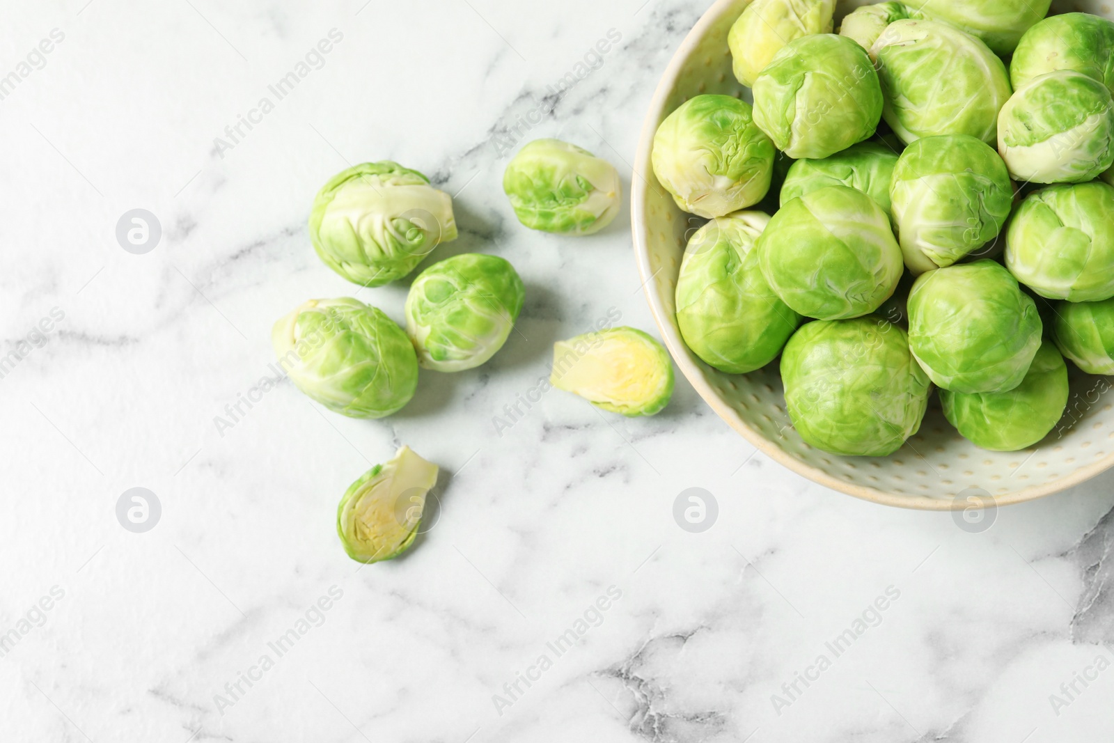 Photo of Bowl with fresh Brussels sprouts on marble table, top view. Space for text