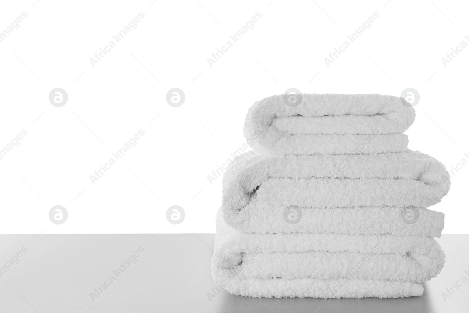 Photo of Fresh towels on light grey table against white background. Space for text