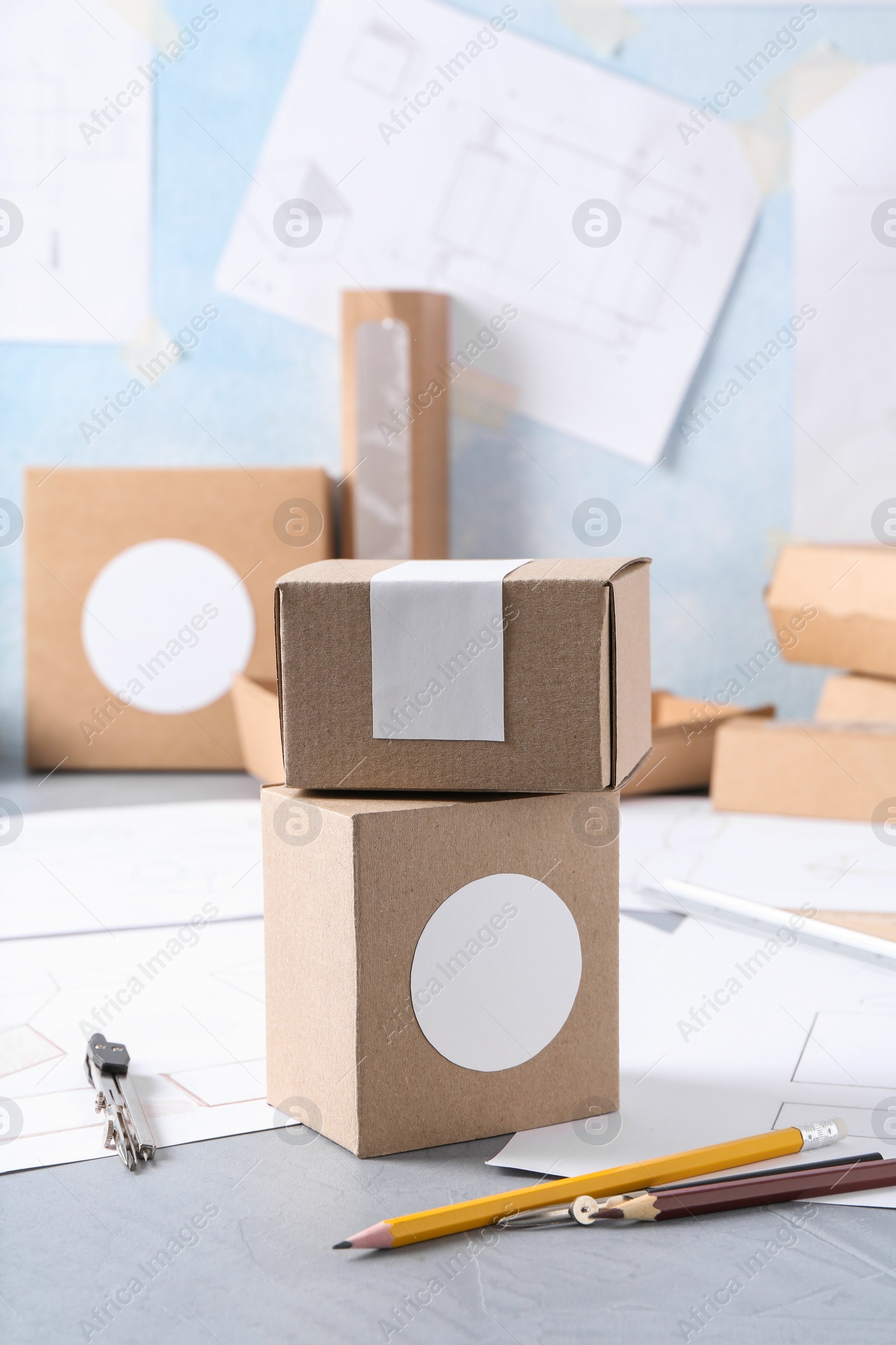 Photo of Creating packaging design. Drawings, boxes and stationery on blue textured table, closeup