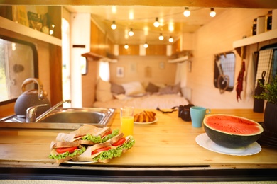 Delicious sandwiches and watermelon on wooden table in modern trailer. Camping vacation