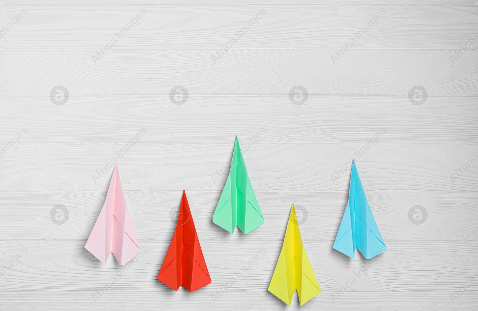 Photo of Different handmade paper planes on white wooden table, flat lay. Space for text