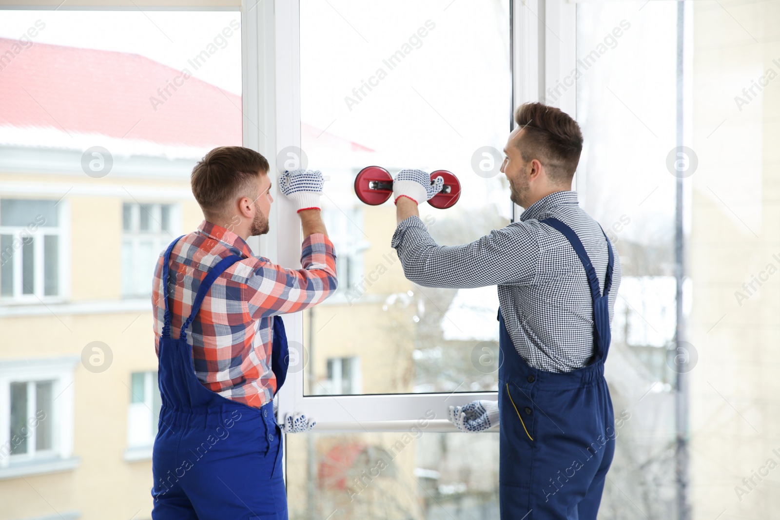 Photo of Construction workers installing plastic window in house