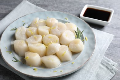 Raw scallops with lemon zest and rosemary on grey marble table, closeup