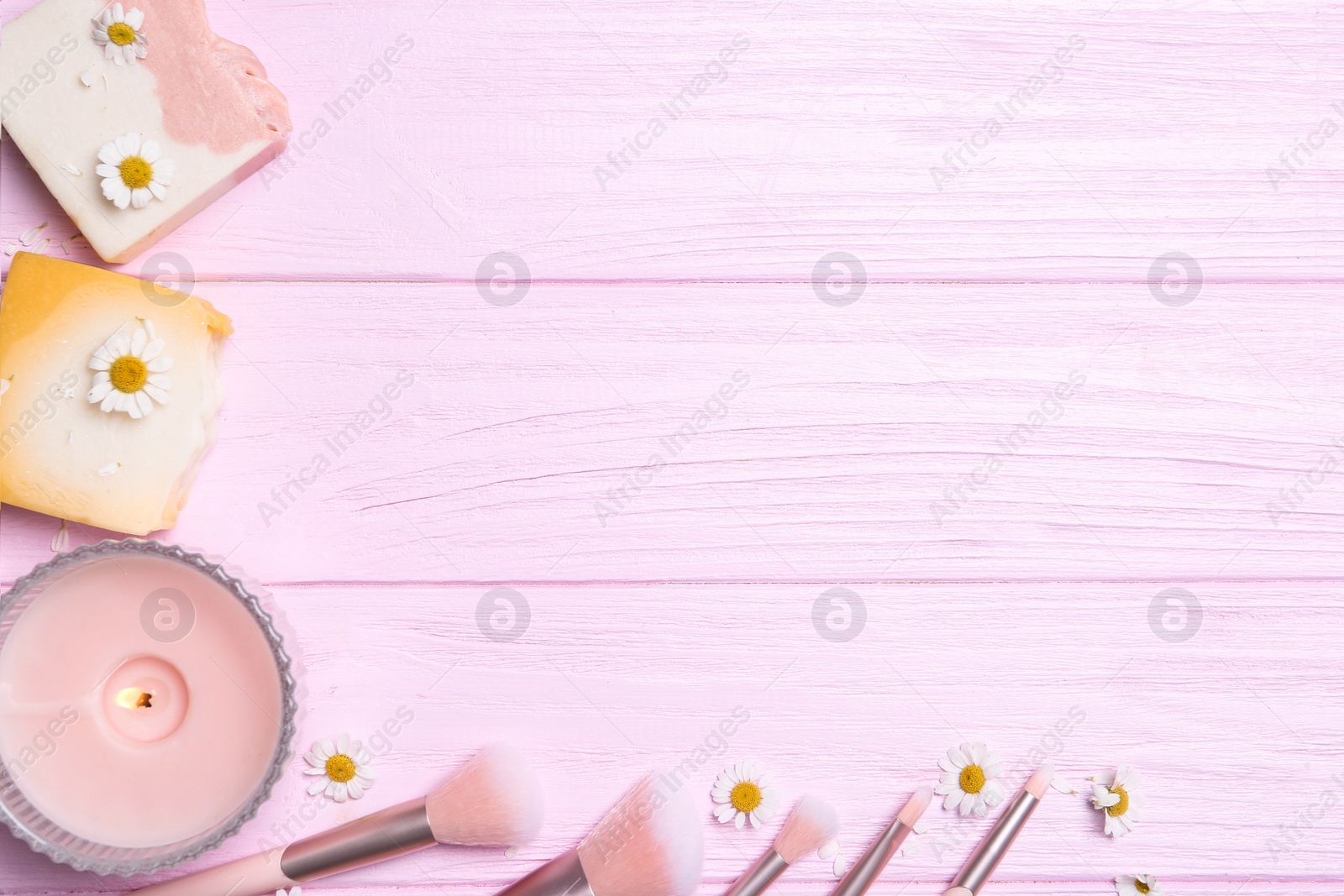 Photo of Flat lay composition with chamomile flowers and soap bars on pink wooden table. Space for text