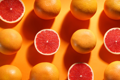 Photo of Cut and whole ripe grapefruits on orange background, flat lay