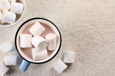 Cup of aromatic hot chocolate with marshmallows on beige table, flat lay. Space for text