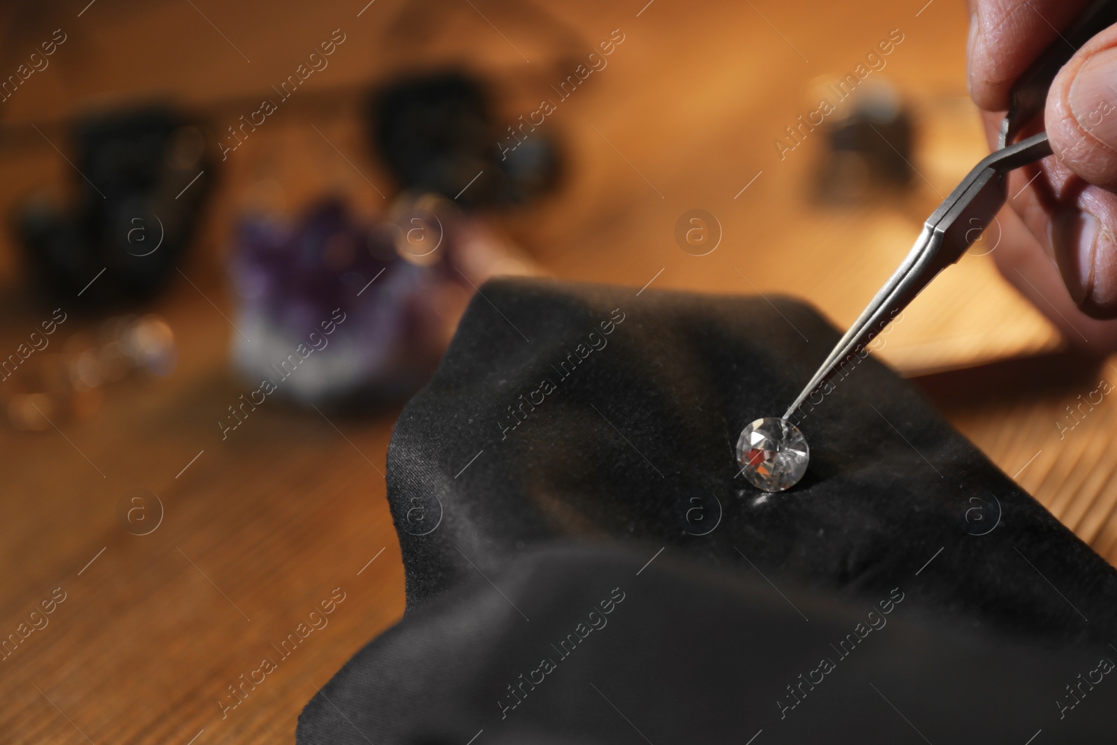 Photo of Professional jeweler working with beautiful gemstone at table, closeup