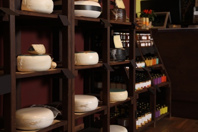 Different types of delicious cheeses on rack in store