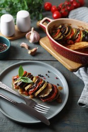 Photo of Delicious ratatouille served with basil on grey wooden table
