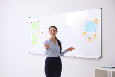 Photo of Young teacher near whiteboard in modern classroom