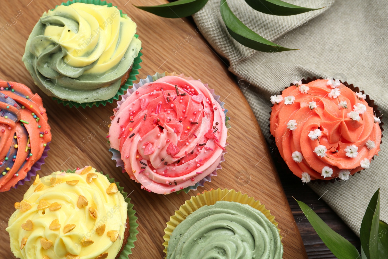 Photo of Delicious cupcake with bright cream on wooden table, flat lay