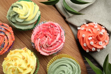 Photo of Delicious cupcake with bright cream on wooden table, flat lay