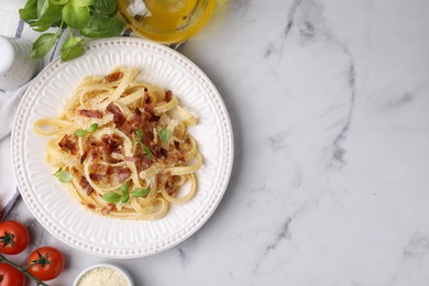 Photo of Tasty pasta with bacon and basil on white marble table, flat lay. Space for text