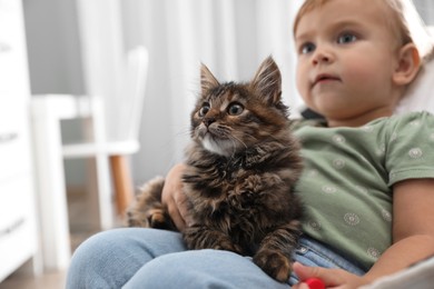 Photo of Cute little child with adorable pet sitting in armchair at home