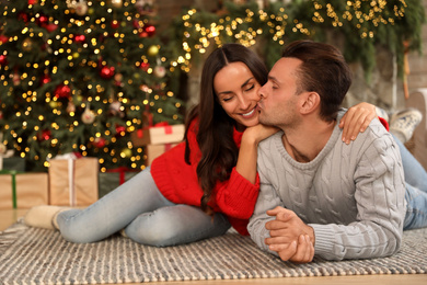 Photo of Happy young couple lying on floor in living room decorated for Christmas