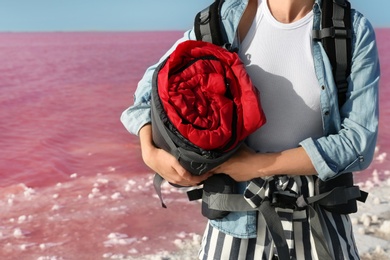 Woman with sleeping bag on coast of pink lake