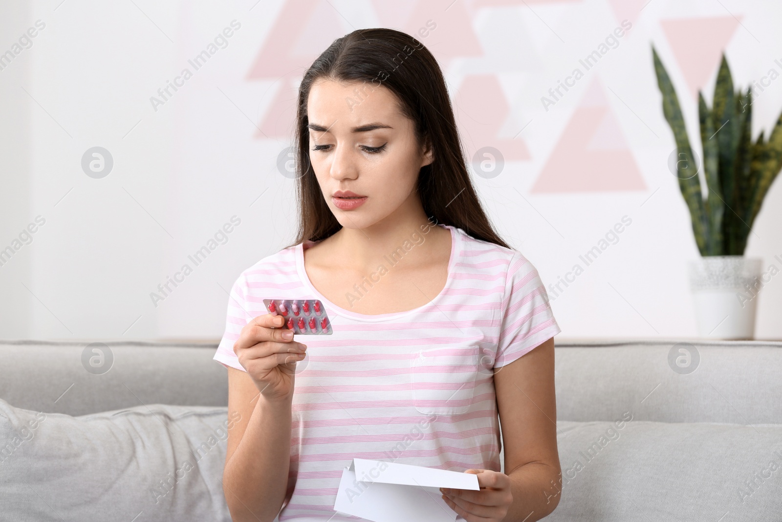 Photo of Beautiful young woman with pills at home