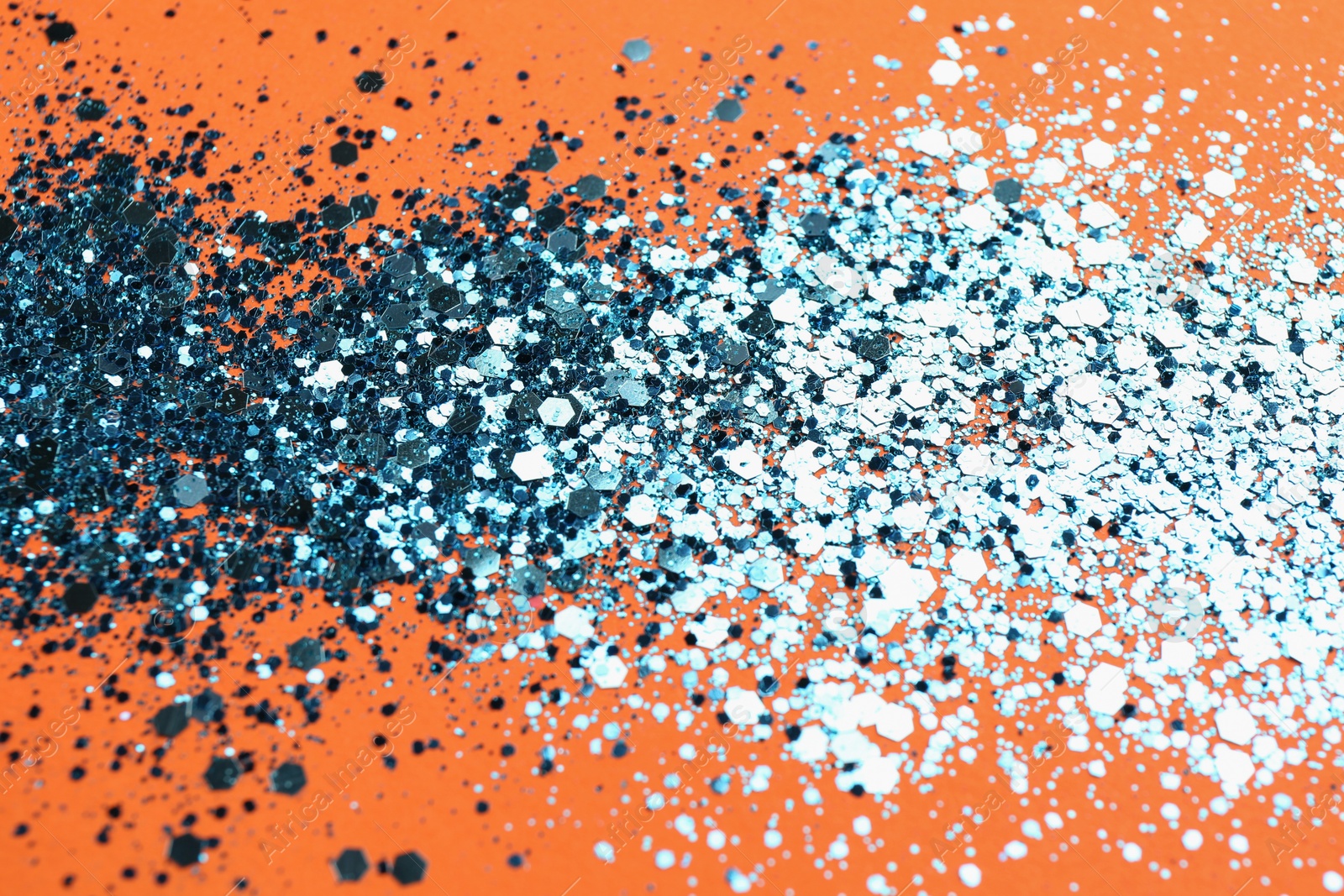 Photo of Shiny bright blue glitter on orange background