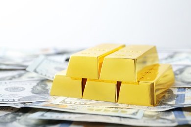 Photo of Shiny gold bars and dollar bills on white background