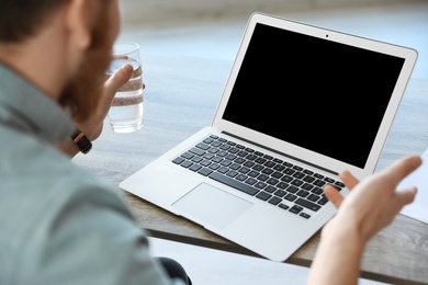 Man using video chat on laptop in home office, closeup. Space for text