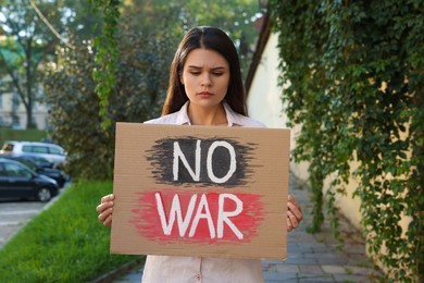 Photo of Sad woman holding poster with words No War on city street