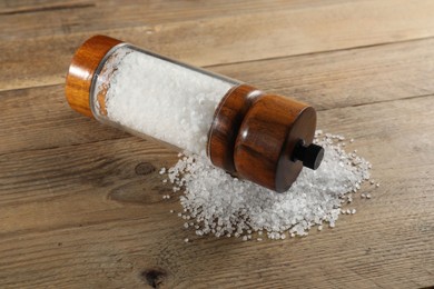 Photo of Shaker with salt on wooden table, closeup