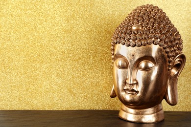 Photo of Buddha statue on table against golden background. Space for text