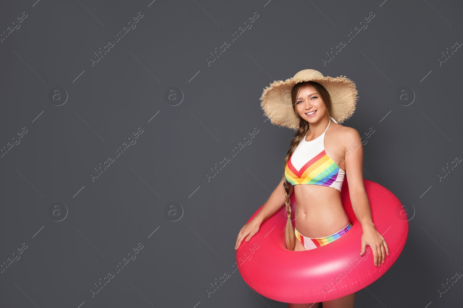 Photo of Beautiful young woman in bikini with inflatable ring against dark background. Space for text