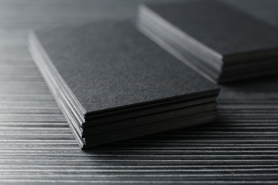 Photo of Blank black business cards on wooden table, closeup