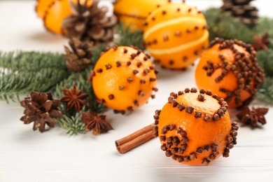 Photo of Pomander balls made of fresh tangerines with cloves  on white wooden table, space for text. Christmas atmosphere